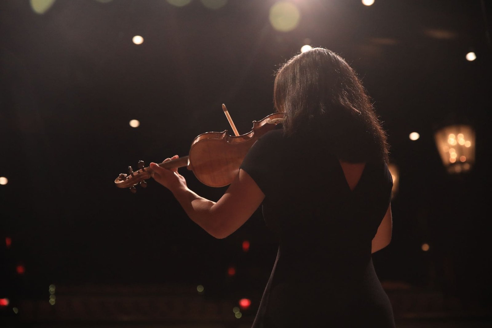 Mari Roes performing violin on stage under warm lights